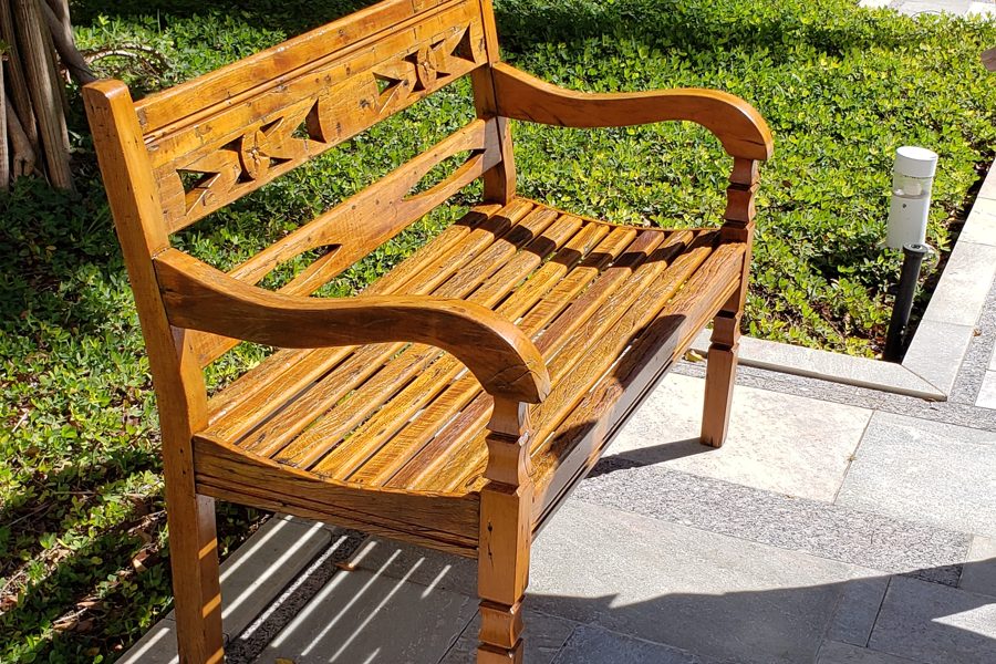 Banco de madeira maciça com encosto vazado, instalado em um jardim
