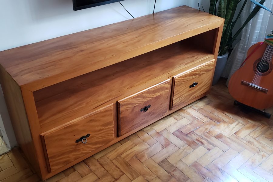 Rack baixo de madeira maciça com duas gavetas, em uma sala com piso de tacos