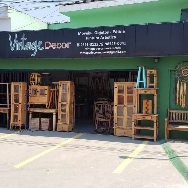 Fachada verde da loja Vintage Decor com móveis de madeira expostos na calçada