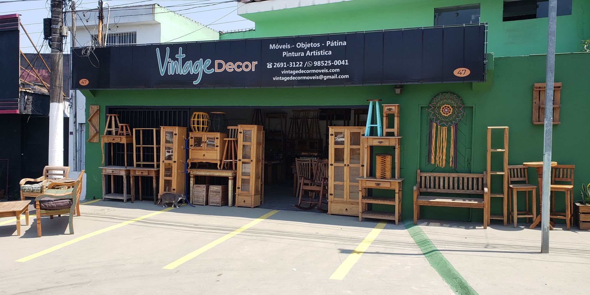 Fachada da Vintage Decor na Rua Antônio Gomide: parede verde, faixa preta com o nome da loja e móveis de madeira expostos na calçada